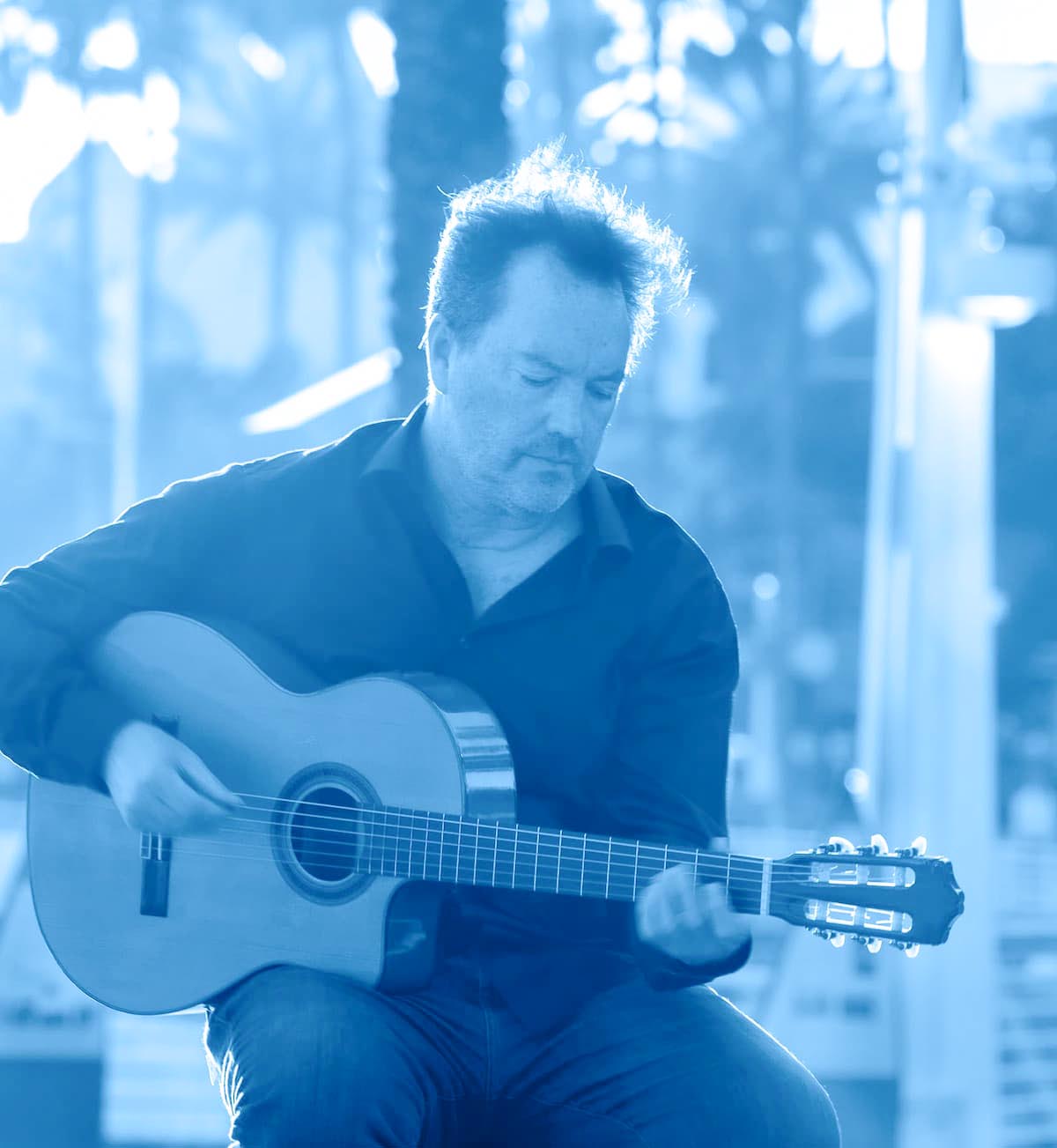 Marcus Gerakos playing classical guitar in blue stage-like light